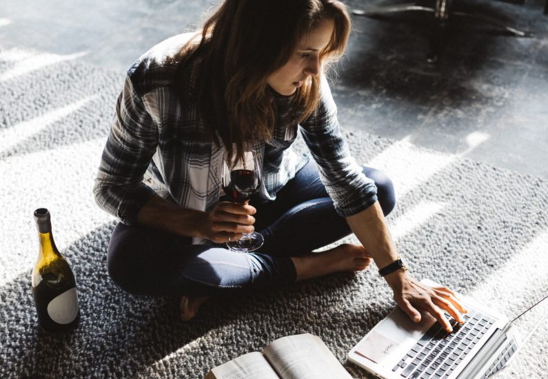 donna lavori con bicchiere di rosso vino e il computer portatile nel bar.  donna utilizzando il computer portatile mentre avendo vino a ristorante.  libero professionista 19038482 Stock Photo su Vecteezy